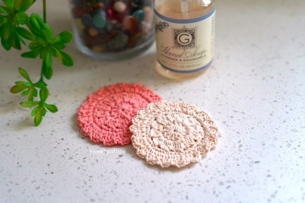 Two pretty pink crochet face scrubbies and a candle.