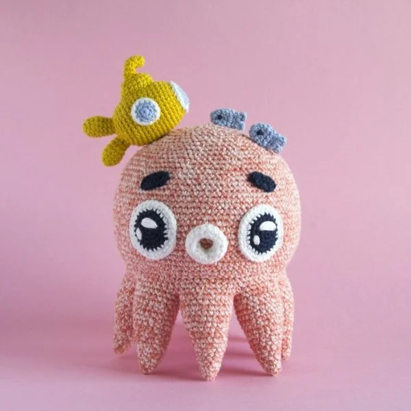 A cute crochet octopus with a tiny submarine and fish on its head.