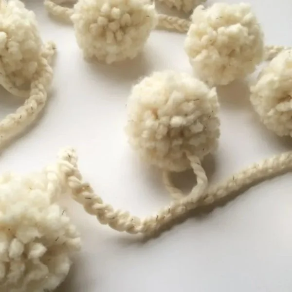A white crochet garland with pompoms.