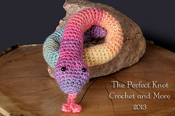 A crochet rainbow snake on a rock.