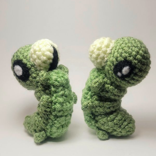 Two green caterpillars standing and facing each other.
