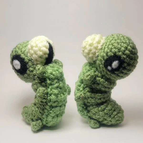 Two green caterpillars standing and facing each other.