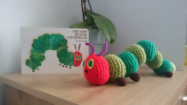 A crochet version of the Very Hungry Caterpillar nect to the book by Eric Carle.