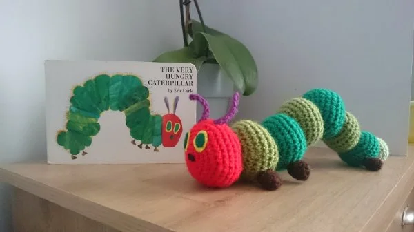 A crochet version of the Very Hungry Caterpillar nect to the book by Eric Carle.