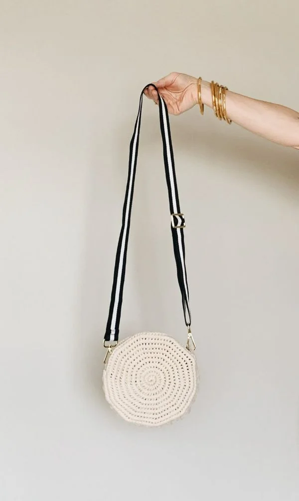 A crochet circle bag with a long crossbody strap.