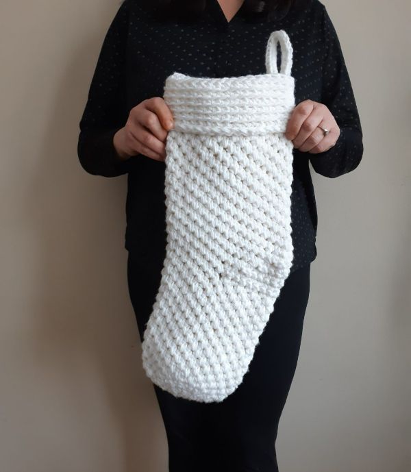 A womna holding a jumbo crochet Christmas stocking.