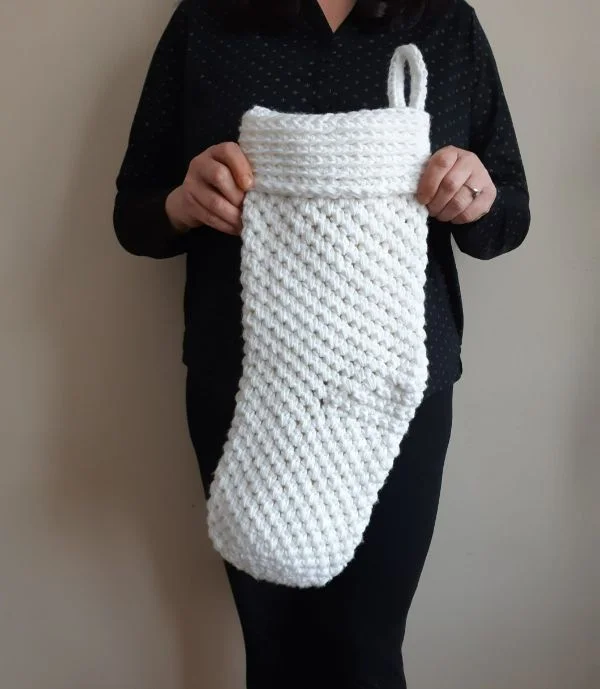 A womna holding a jumbo crochet Christmas stocking.