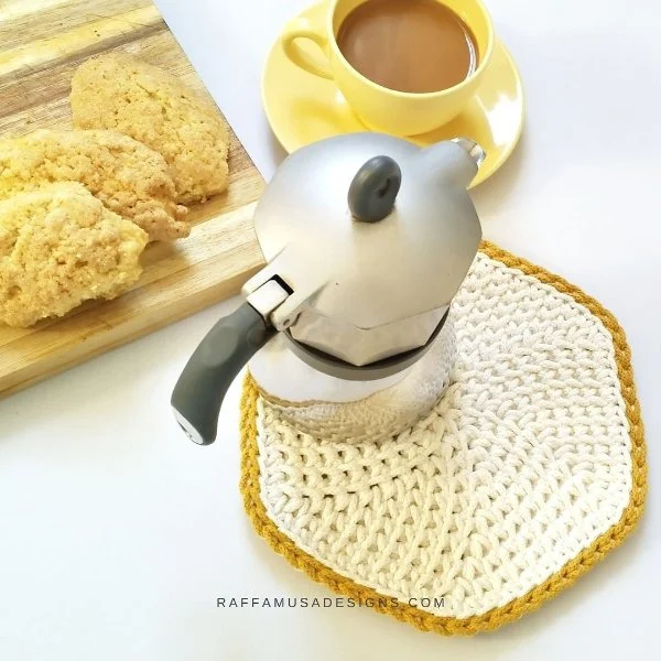 A coffee pot on a yellow and white crochet trivet.