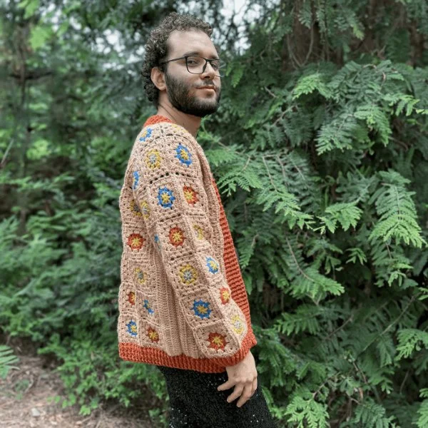 A man wearing a floral crochet granny square cardigan.