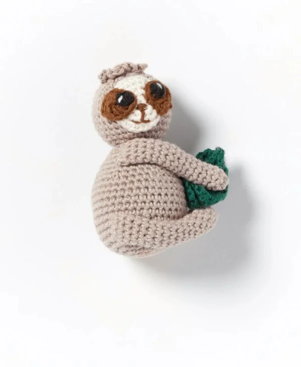 A small crochet sloth on a white background.