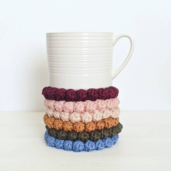 A stack of crochet coasters with bobble stitch edging.