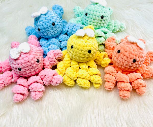 A pile of crochet octopi with bows on their heads.
