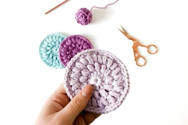 A closeup of a hand holding a crochet face pad.