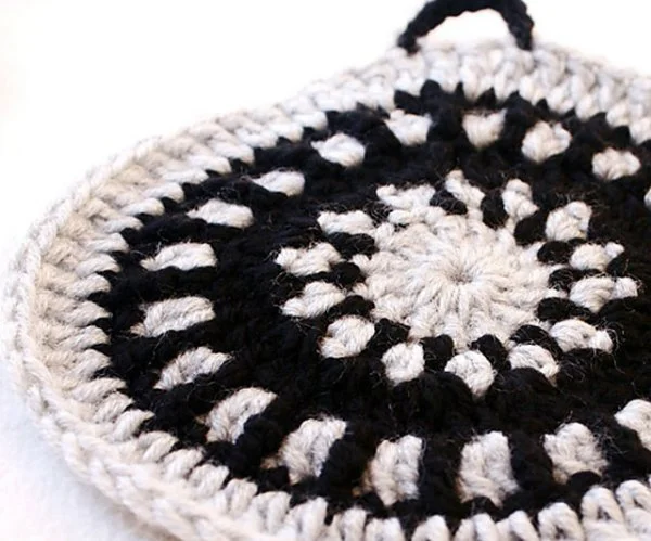 A closeup of a black and white crochet trivet.