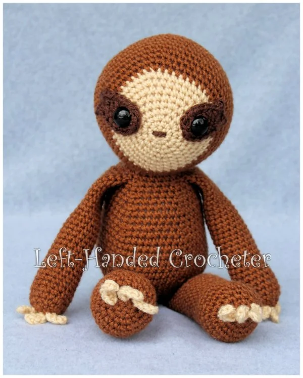 A brown crochet sloth on a blue background.