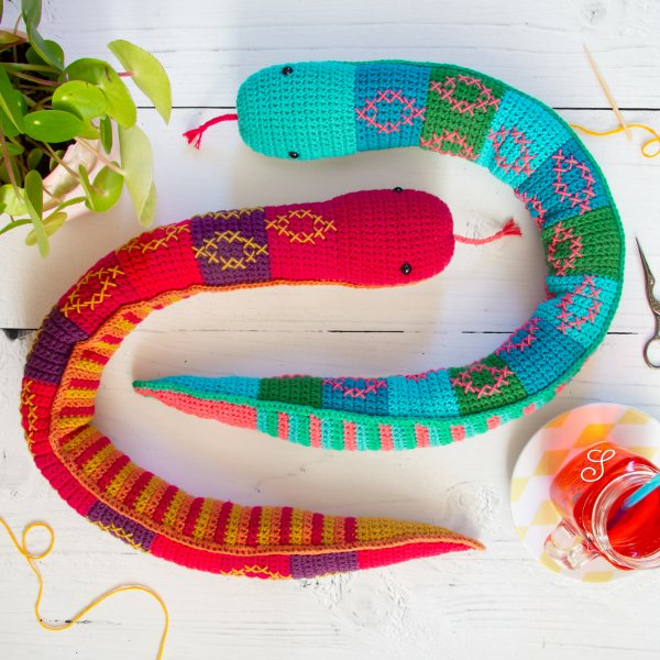 Two brightly coloured crochet snakes with embroidered details.