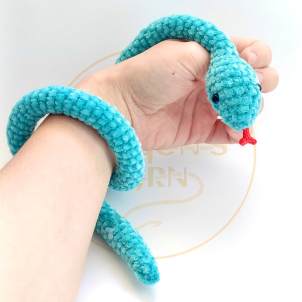 A small blue crochet snake coiled around an arm.