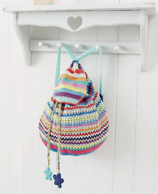 A colourful, striped crochet backpack hanginn on a wall hook.