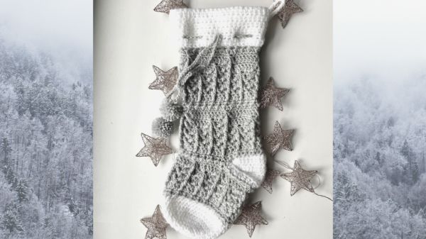 A grey and white crochet stocking with cable stitch pine trees.