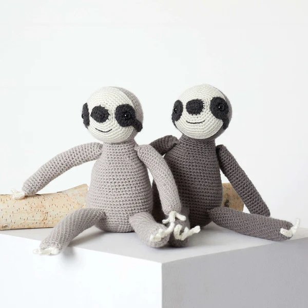 Crochet sloths made in grey toned yarn.