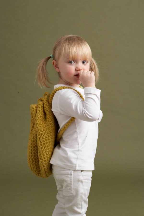 A toddler wearing a crochet backpack.
