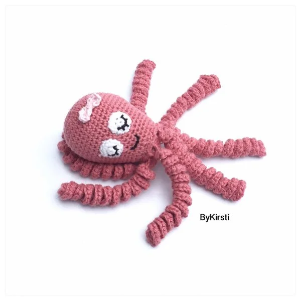 A pink crochet baby octopus with a bow.