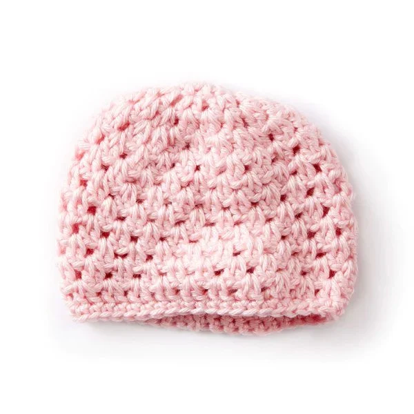 A flat lay image of a pink  crochet newborn baby hat on a white background.