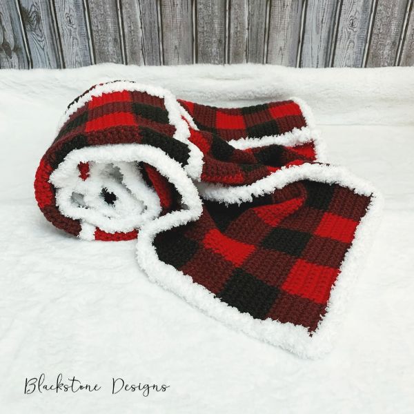 A buffalo plaid crochet Christmas blanket with faux fur trim.