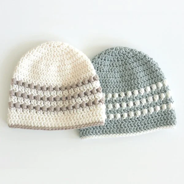 Two crochet baby hats with contrasting puff stitch stripes.