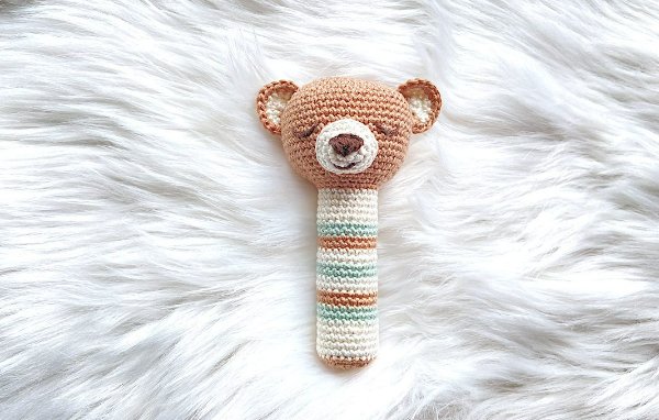 A bear-themed crochet rattle on a background of white fur.