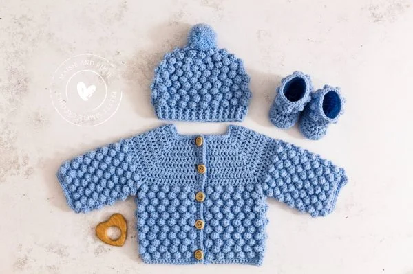 A crochet newborn baby hat with a matching baby cardigan and booties.