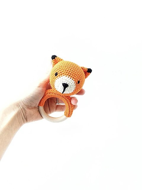 A crochet fox rattle on a wooden teething ring.