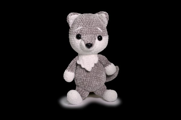A close up of a grey and white crochet wolf amigurumi on a black background.