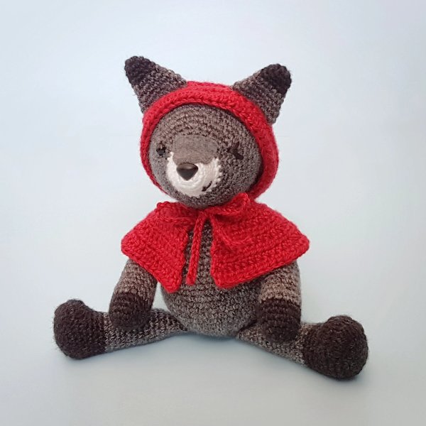 A crochet wolf toy with a red cape.