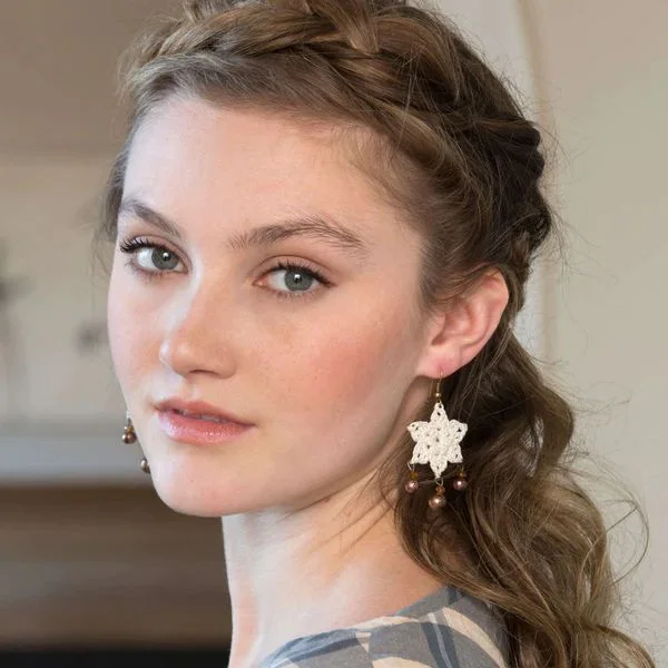 A woman wearing dangling crochet flower earrings.