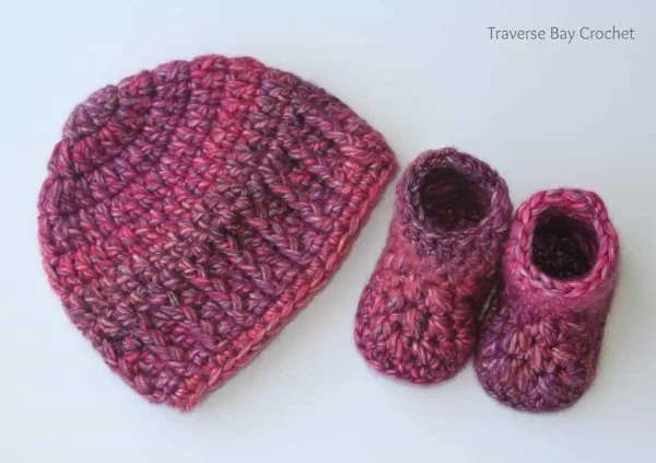 A crochet newborn hat with matching booties.
