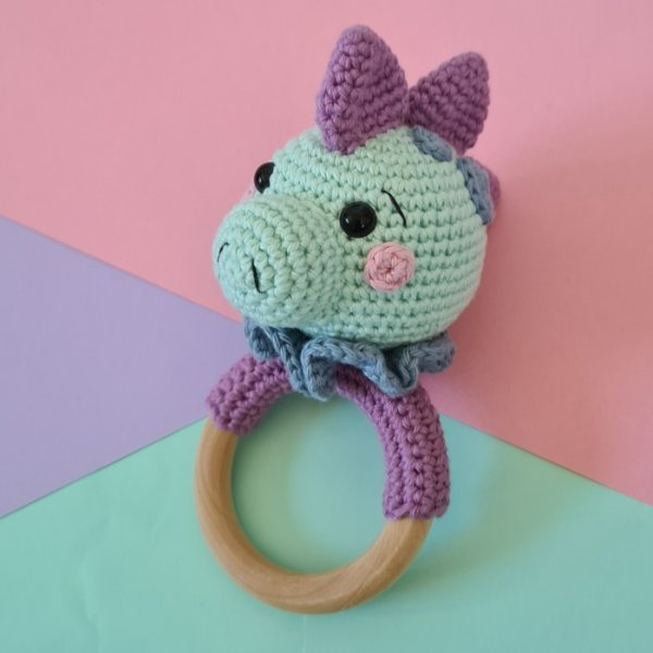 A crochet dinosaur rattle made in bright pastels.