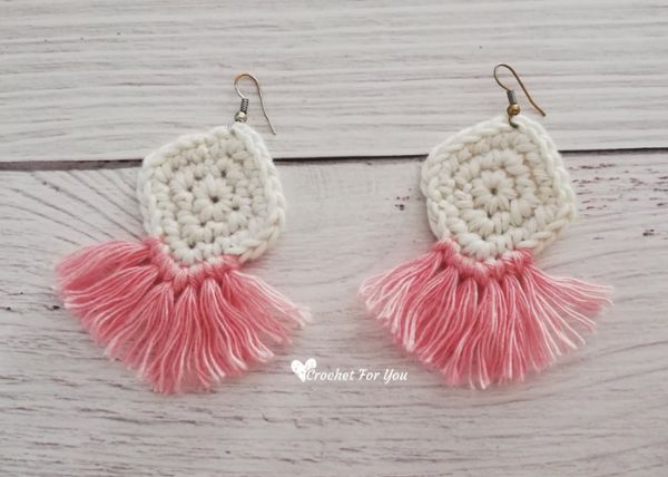 White diamond-shaped crochet earrings with pink tassels.