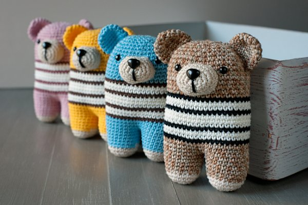 A row of four different coloured bear-themed crochet rattles.