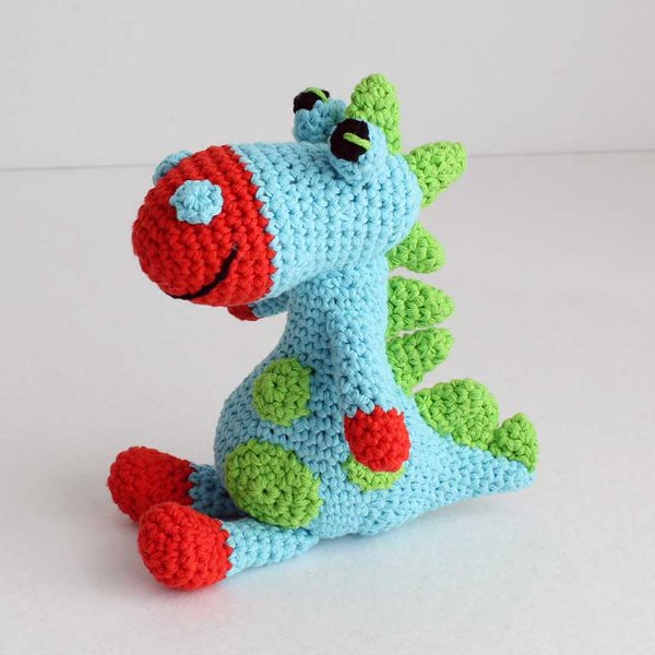 A sitting crochet dinosaur made in brightly coloured yarn.