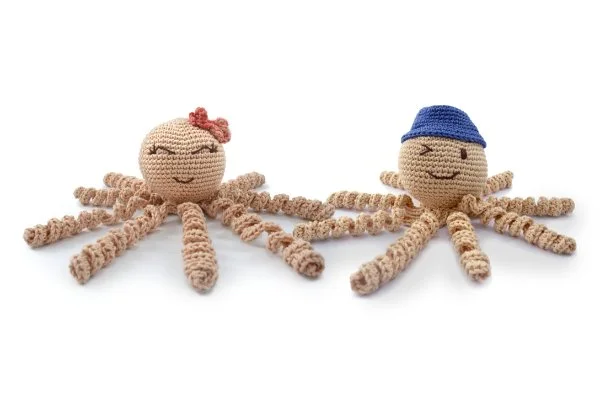 Two long-legged crochet octopus toys: a boyt with a hat and a girl with a bow.