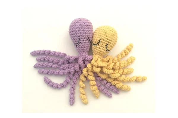 Two sleepy amigurumi octopus toys cuddled up together.