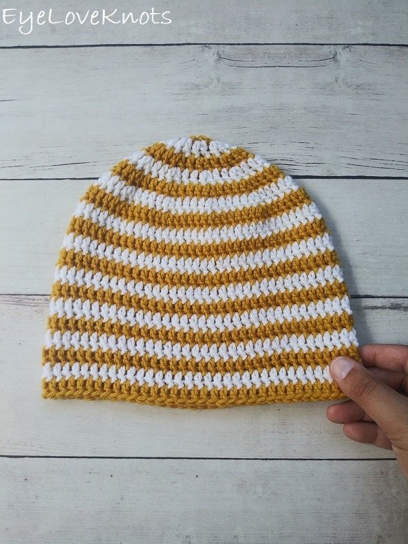 A mustard yellow and white striped baby beanie.