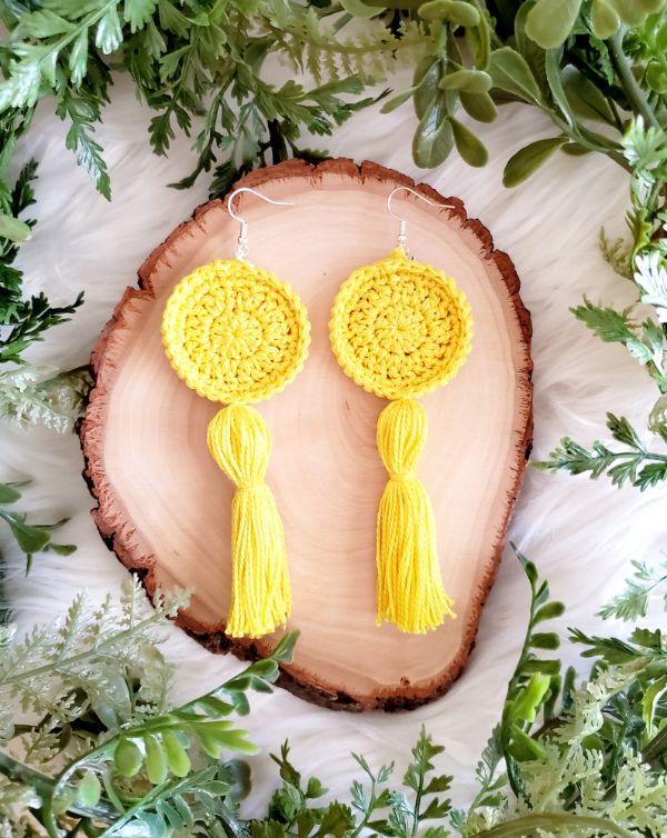 Bright yellow crocheted earrigs with some greenery.