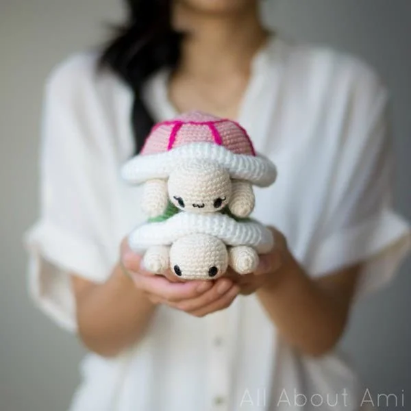A woman holding two amigurumi turtles in her hands.