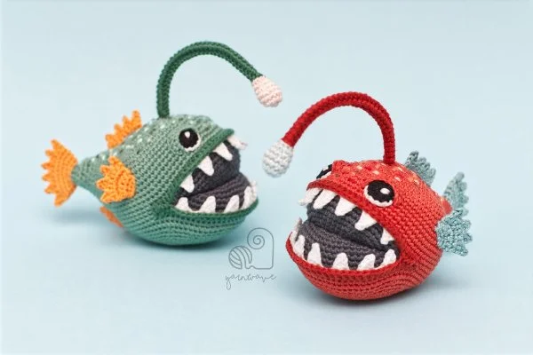 Two crochetd anglerfish made in different colours.