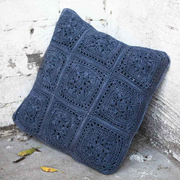 A dark blue granny square crochet pillow.