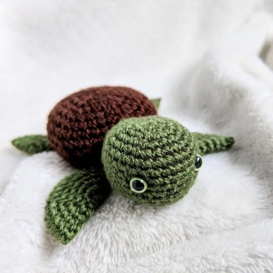 A green and brown crochet baby sea turtle.