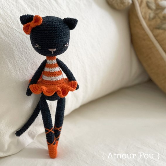 A crochet cat wearing a red and white ballerina outfit.