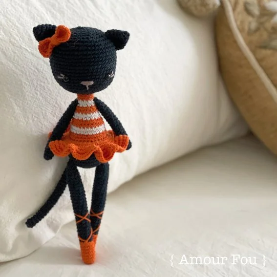 A crochet cat wearing a red and white ballerina outfit.
